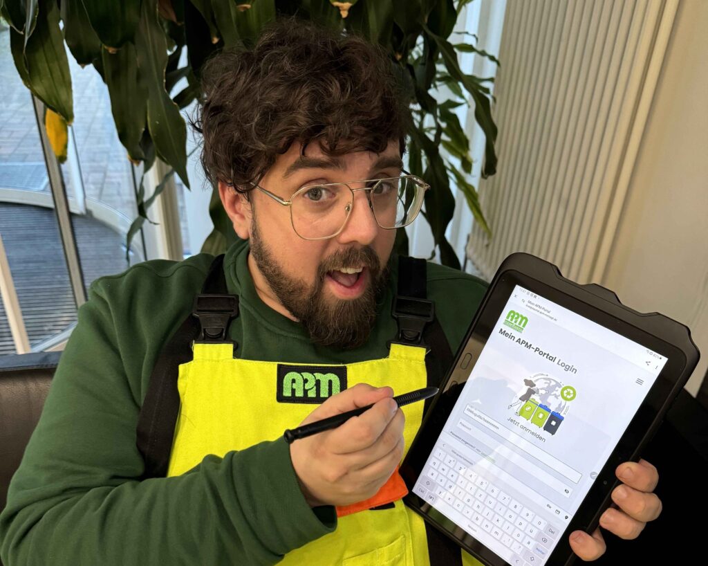 Mann zeigt auf ein Tablet und weist damit auf das APM-Portal hin.