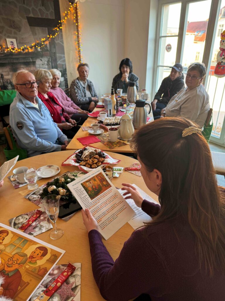 Frau liest Senioren eine Weihnachtsgeschichte vor