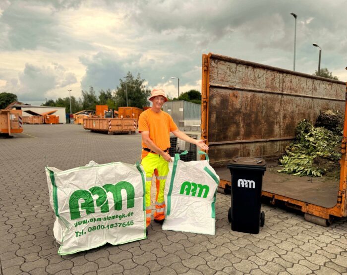 Mann in Orange präsentiert Bigbags, Biotonne und Container